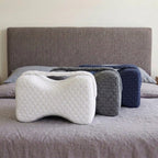 Les trois coussins Noctivelle sur un lit, blanc, gris anthracite et bleu marine