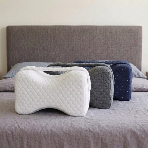 Les trois coussins Noctivelle sur un lit, blanc, gris anthracite et bleu marine