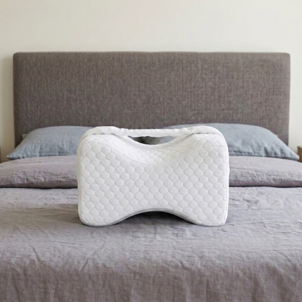 Le coussin Noctivelle blanc, forme sablier, sur un lit
