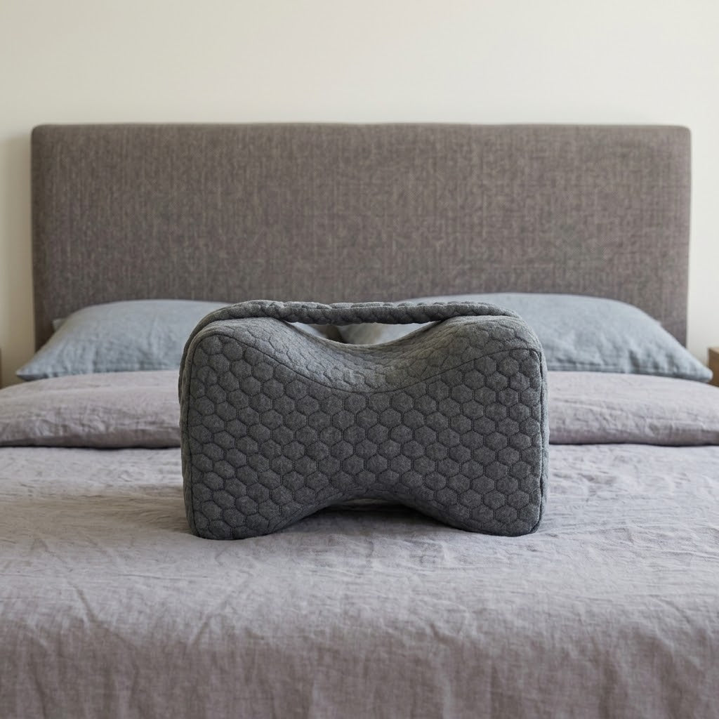Le coussin Noctivelle gris anthracite, forme sablier, sur un lit